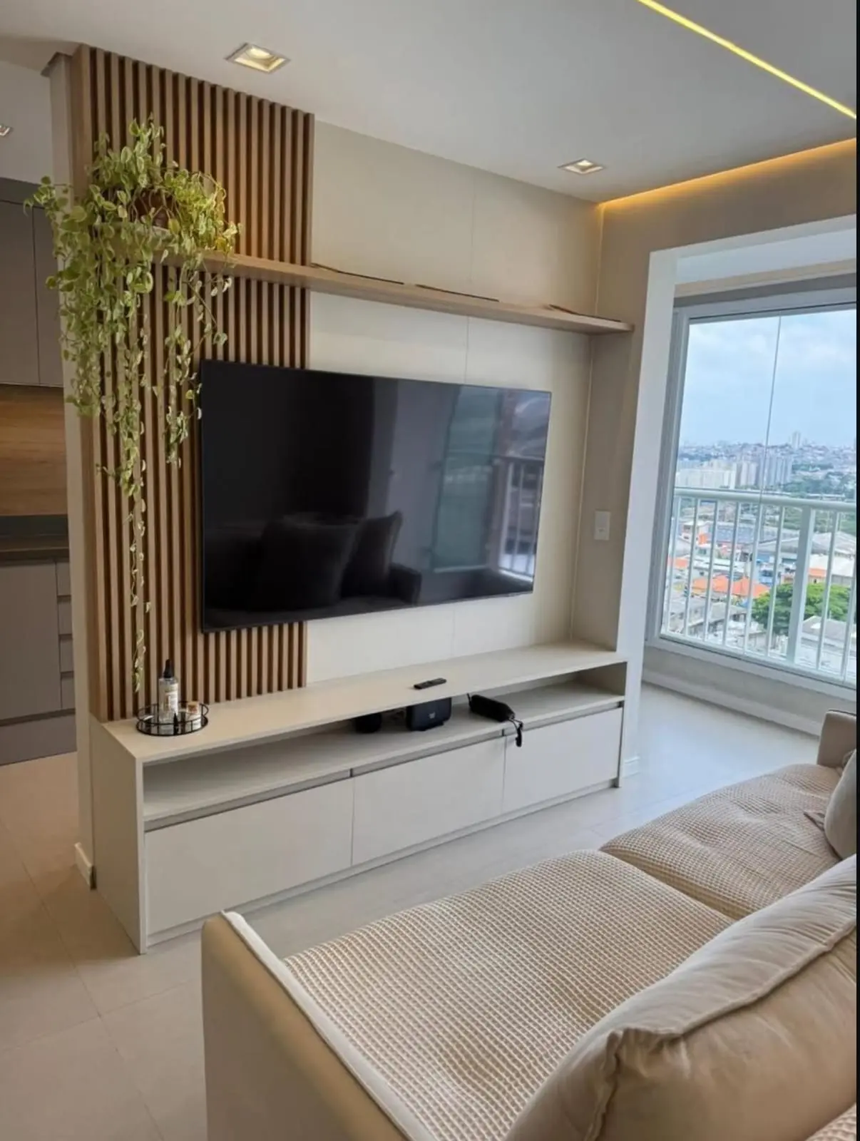 Sala de estar com painel de TV branco e ripado de madeira
