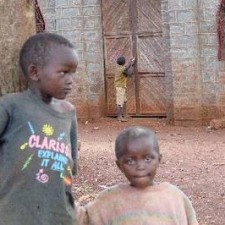 Zwei Kinder aus dem Dorf Makuyu vor einer Backsteinmauer