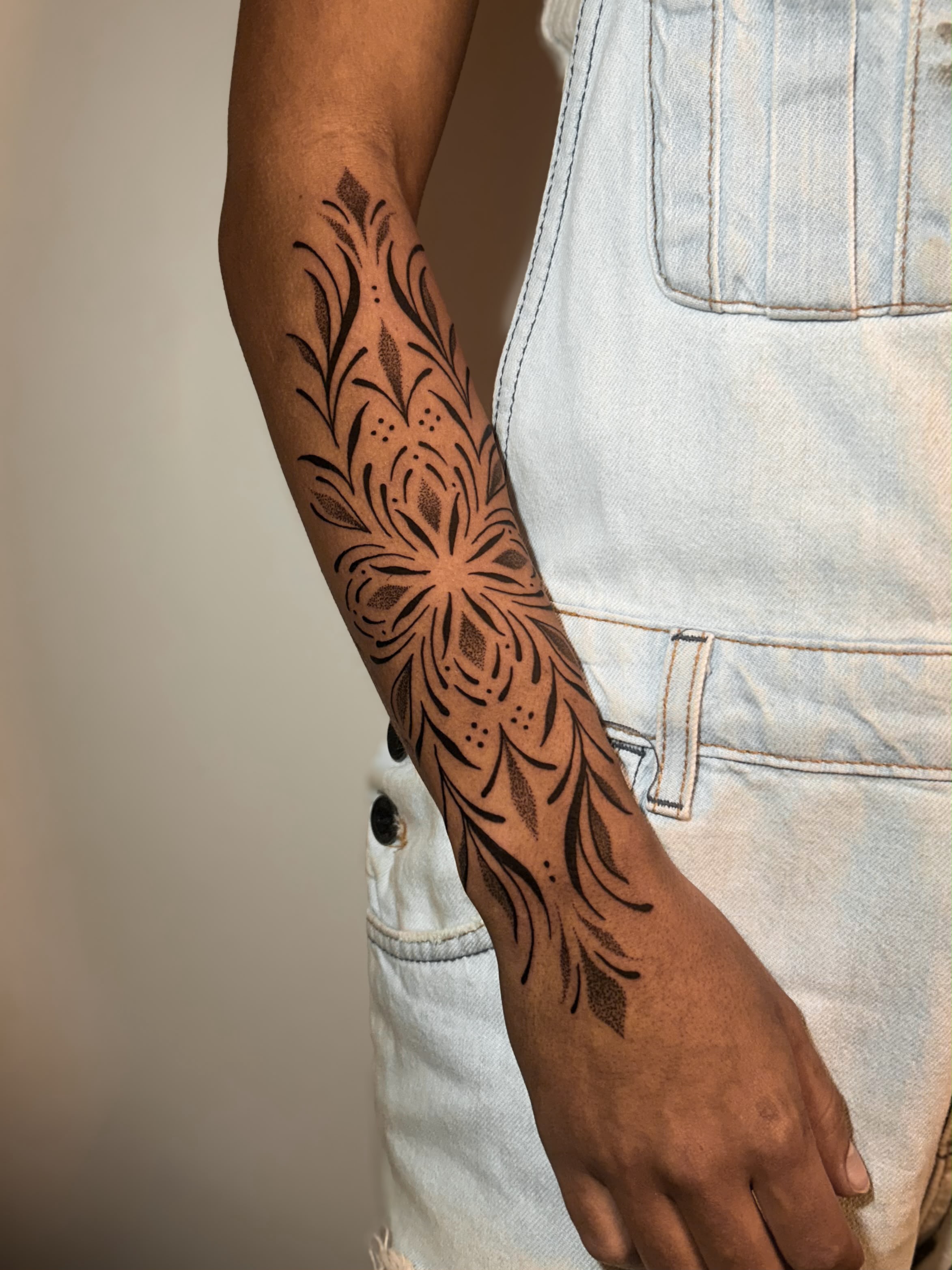 Antebraço com grande mandala floral ornamental, macação jeans