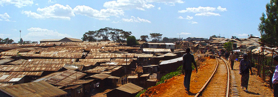 Bahngleise durch eine Township mit Wellblechdächern