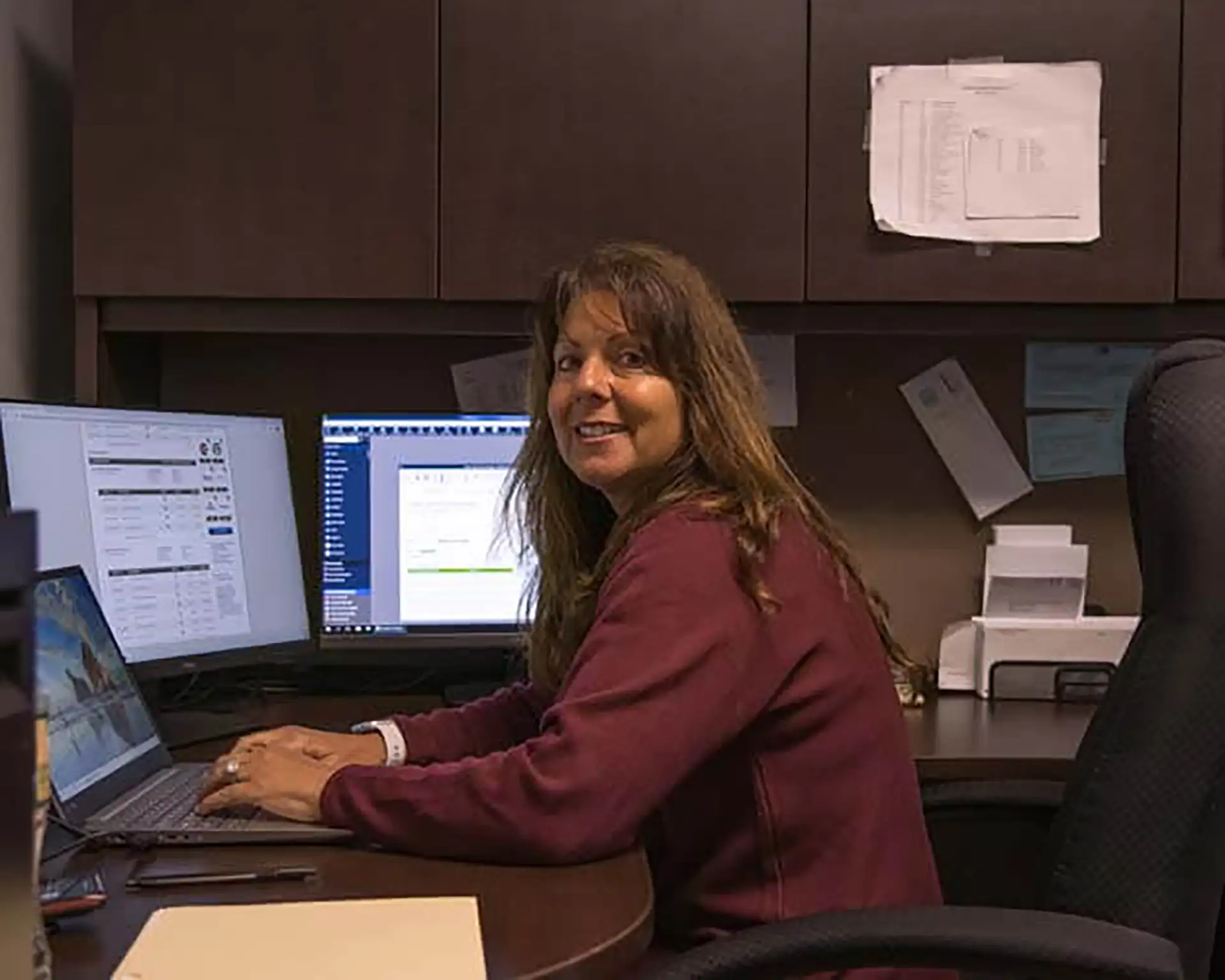 FCS staff member smiling at multi-monitor workstation