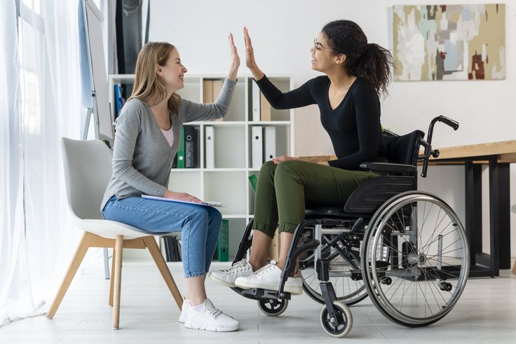 Two people celebrating together, one using a wheelchair