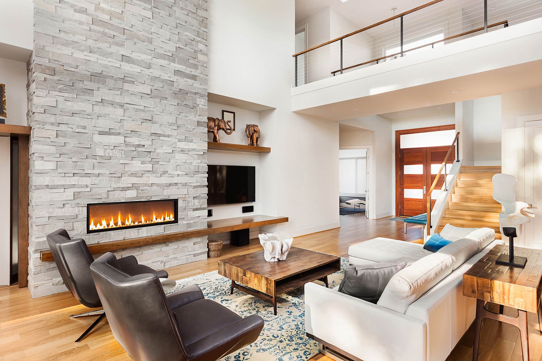 Modern living room with stone fireplace and double-height ceiling