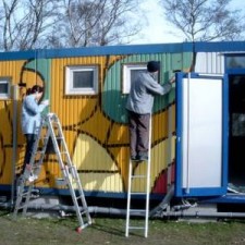 Zwei Arbeiter auf Leitern montieren Tür am Graffiti-Container
