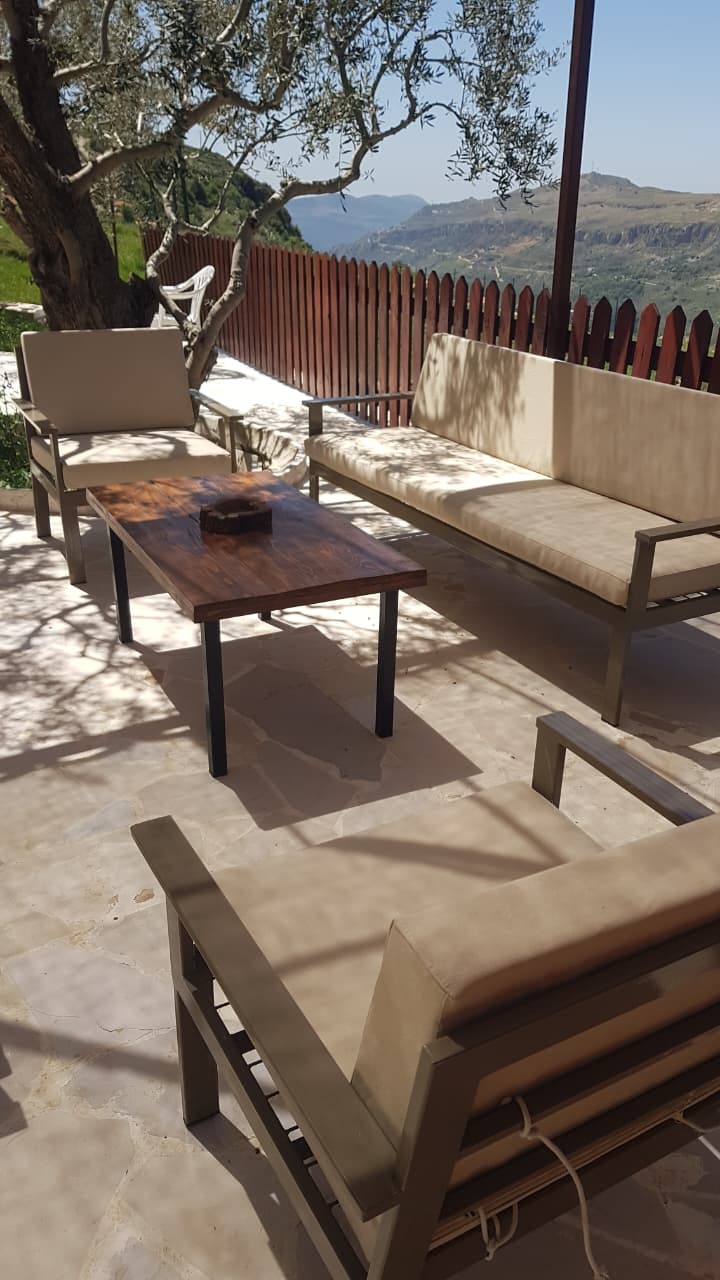 Outdoor terrace lounge seating with mountain valley panorama and olive tree shade