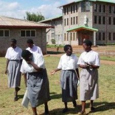 Vier Schülerinnen in Schuluniform vor dem Schulgebäude der Missionsstation
