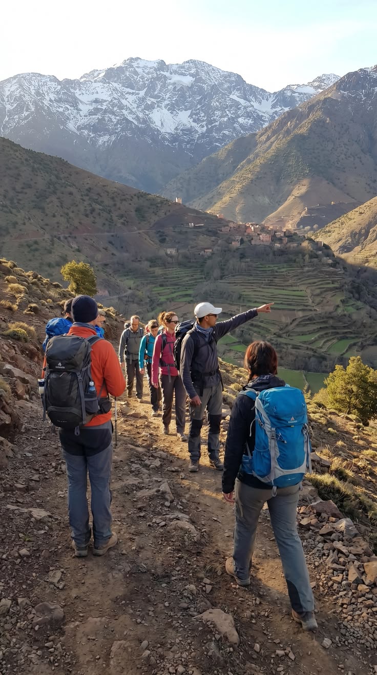 Guide pointing out features to trekkers overlooking valley with terraced fields and villages