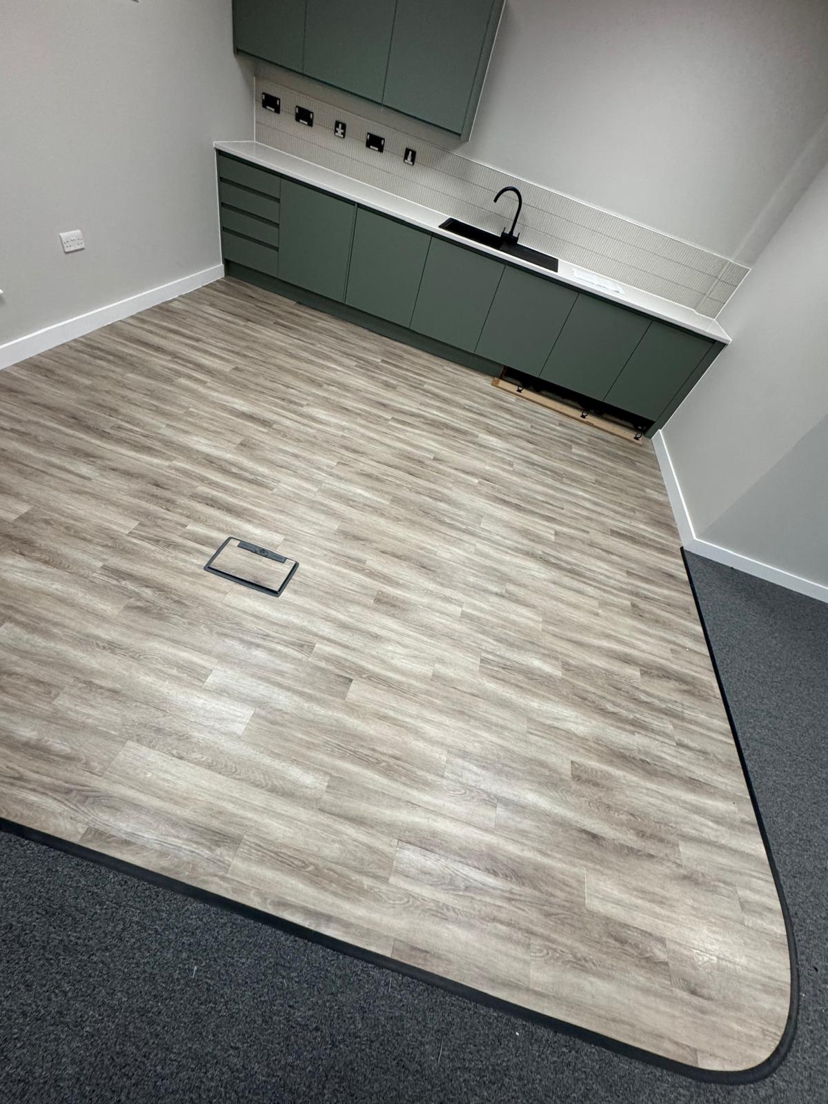 Kitchen area with light wood effect vinyl flooring and curved edge