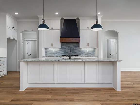 Kitchen with marble island and navy range hood