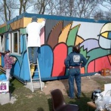Drei Maler auf Leitern beim Bemalen des Containers