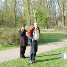 Zwei Männer stehen im Frühling im Park, einer hält Blumen