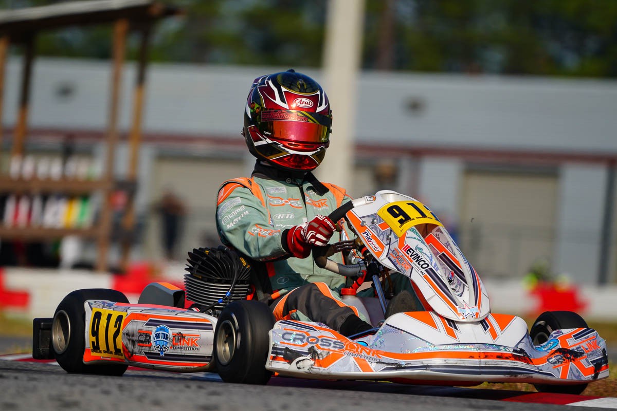 Crosslink Competition kart #912 driver in teal and orange suit with red Arai helmet