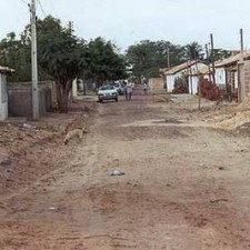 Unbefestigte Dorfstraße mit Auto in der Ferne