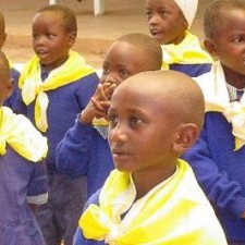 Kindergartenkinder in blauen Uniformen mit gelben Halstüchern schauen aufmerksam