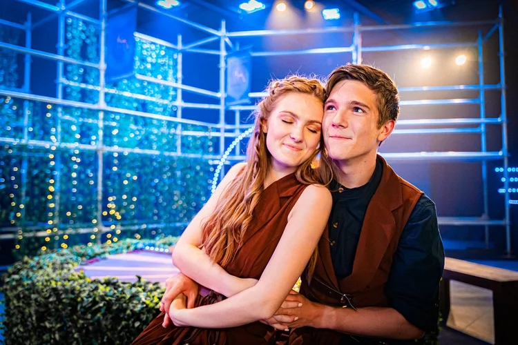 A couple embracing on a softly lit stage