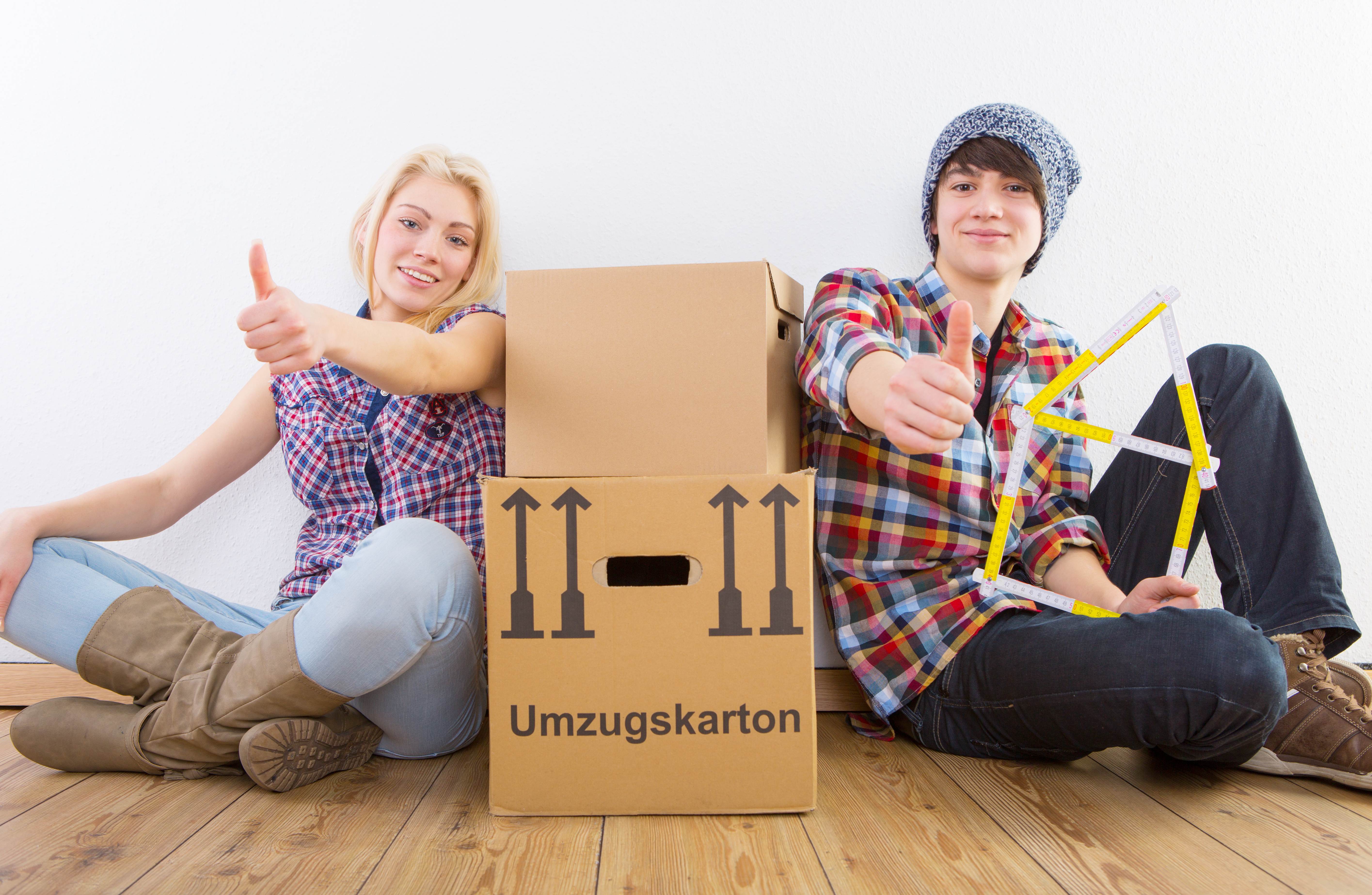 Junge Menschen freuen sich über ihre erste Wohnung beim Umzug