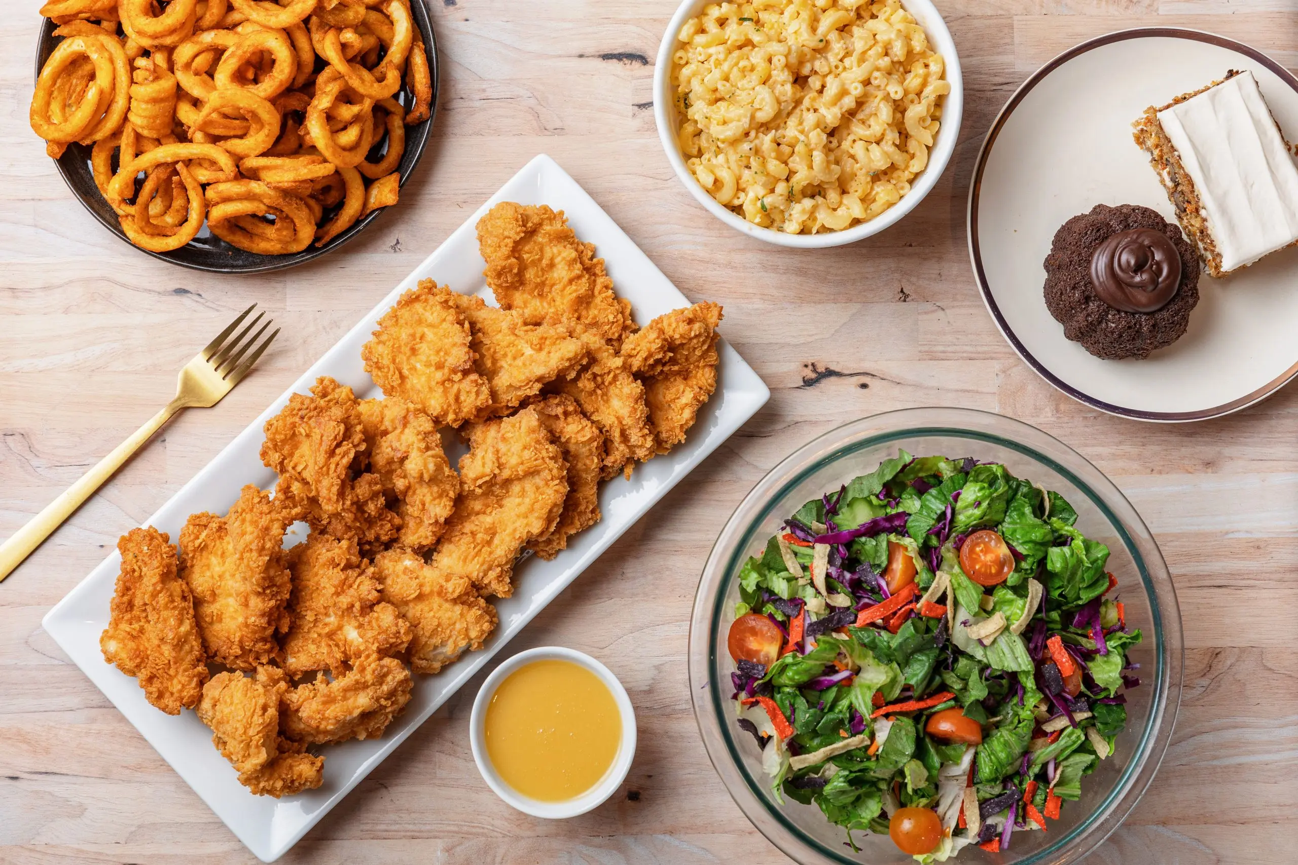 Kluck's Catering spread with crispy chicken tenders, curly fries, mac and cheese, salad and dipping sauce