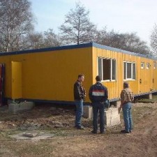 Drei Personen begutachten den aufgestellten Container