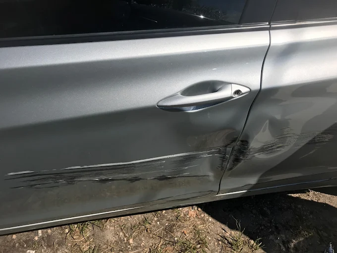 Silver sedan with deep door scrape and gouge awaiting paint and body repair at Factory Finish