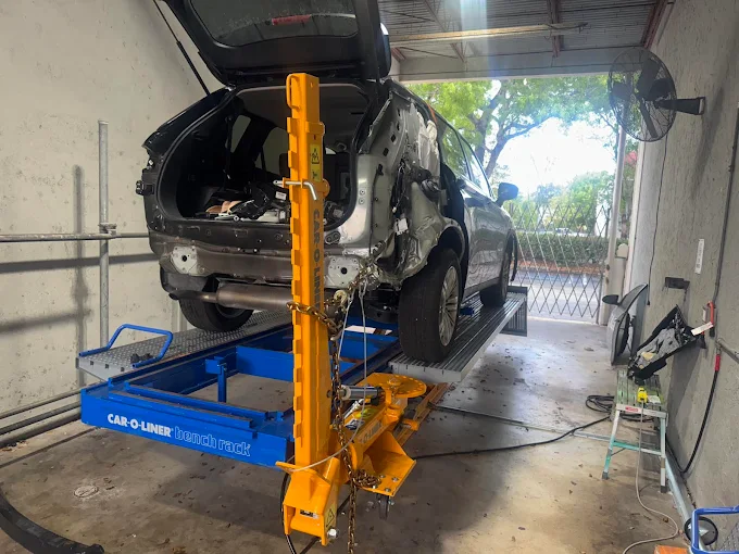 Damaged SUV lifted on a Car-O-Liner bench rack with frame puller engaged at Factory Finish