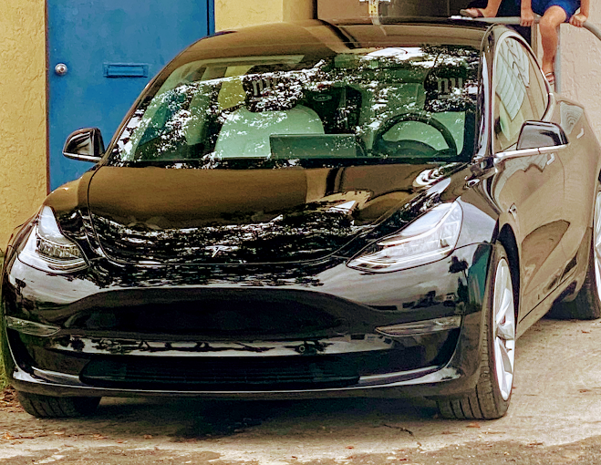 Glossy black Tesla parked outside Factory Finish Paint and Body after refinishing
