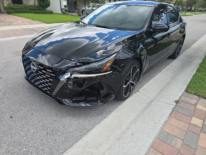 Black Nissan Altima with severe driver-side front-end collision damage at Factory Finish