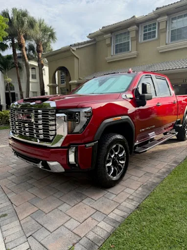 Red GMC Sierra Denali HD pickup parked in an upscale driveway after service at Factory Finish