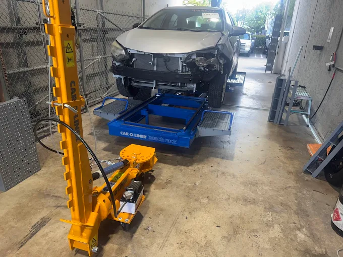 Damaged silver Toyota Corolla mounted on a Car-O-Liner bench rack with frame puller engaged at Factory Finish