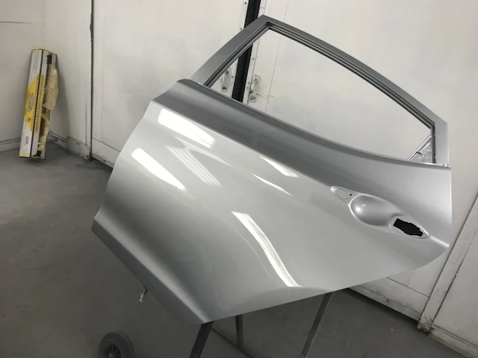 Freshly refinished silver door panel with a flawless paint finish in the Factory Finish spray booth