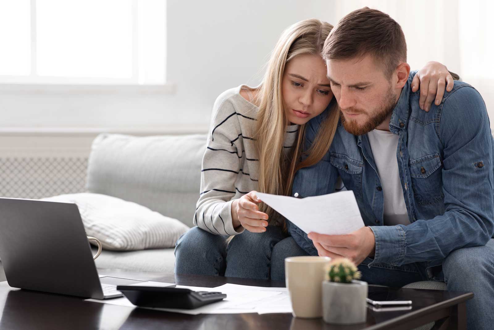 Couple looking concerned while reviewing bills together