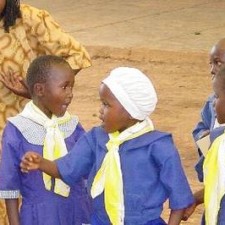 Drei Schülerinnen in blauen Uniformen mit gelben Halstüchern