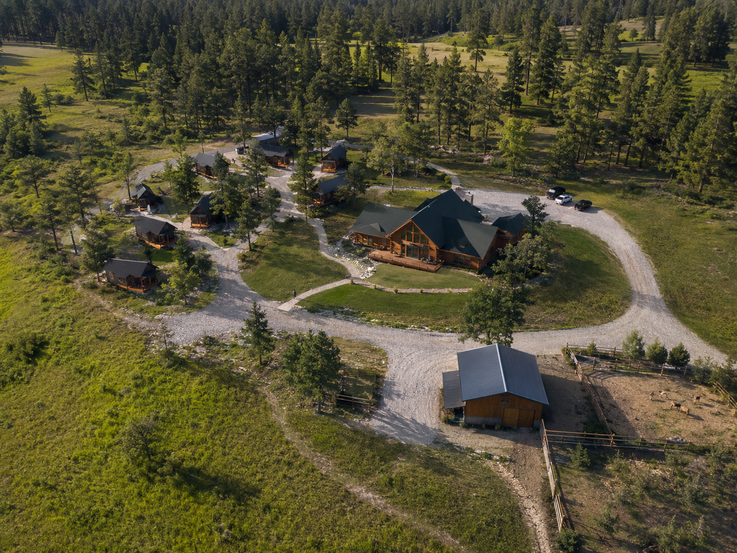 Aerial view of ranch — lodge surrounded by tiny homes among pines