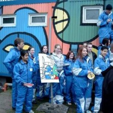 Jugendliche in blauen Overalls halten Bild vor dem Container