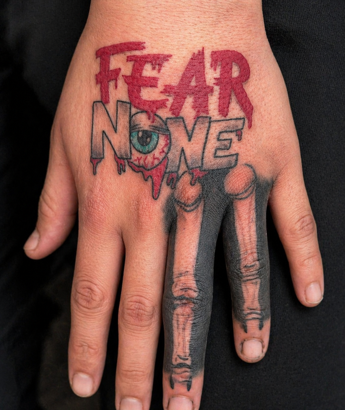 Hand tattoo reading FEAR NONE in dripping red letters with bone fingers