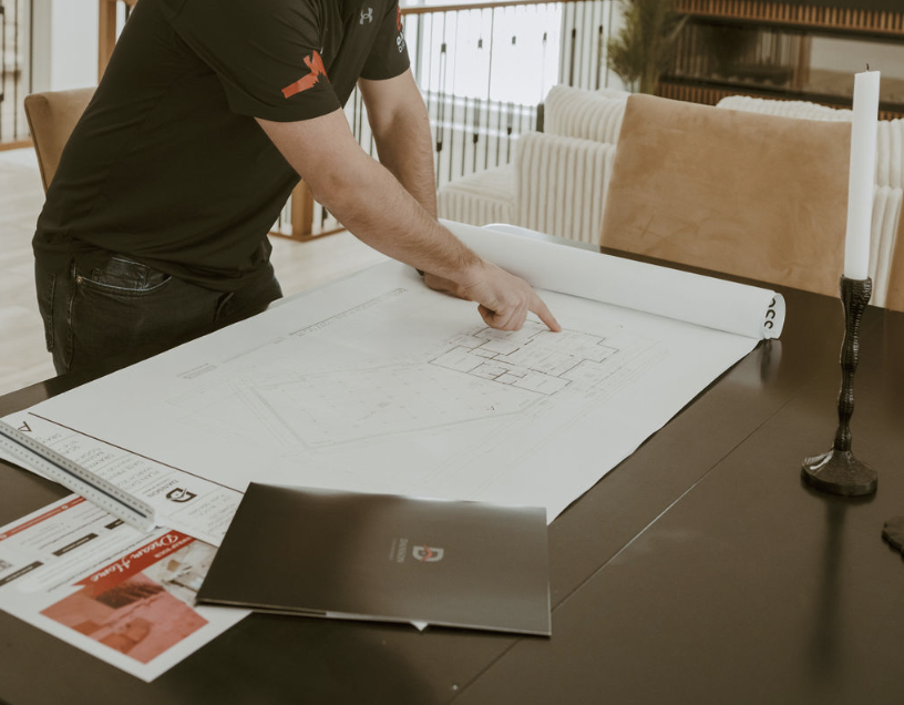 Builder reviewing blueprints and floor plans at table