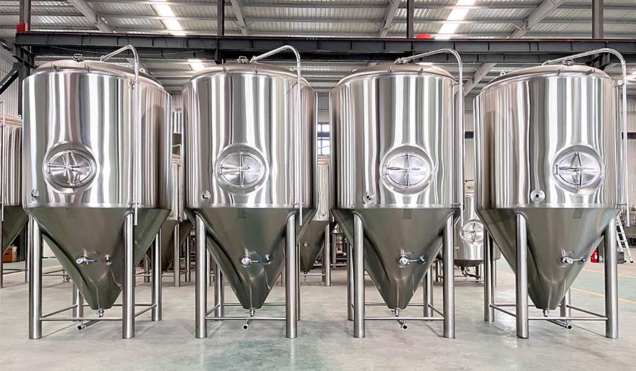 Four conical fermentation tanks in industrial warehouse