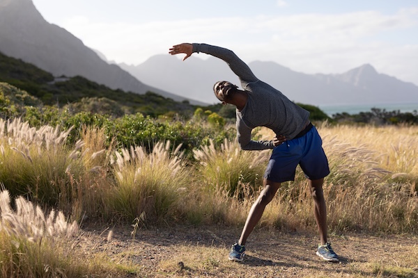 Person stretching outdoors with mountain backdrop