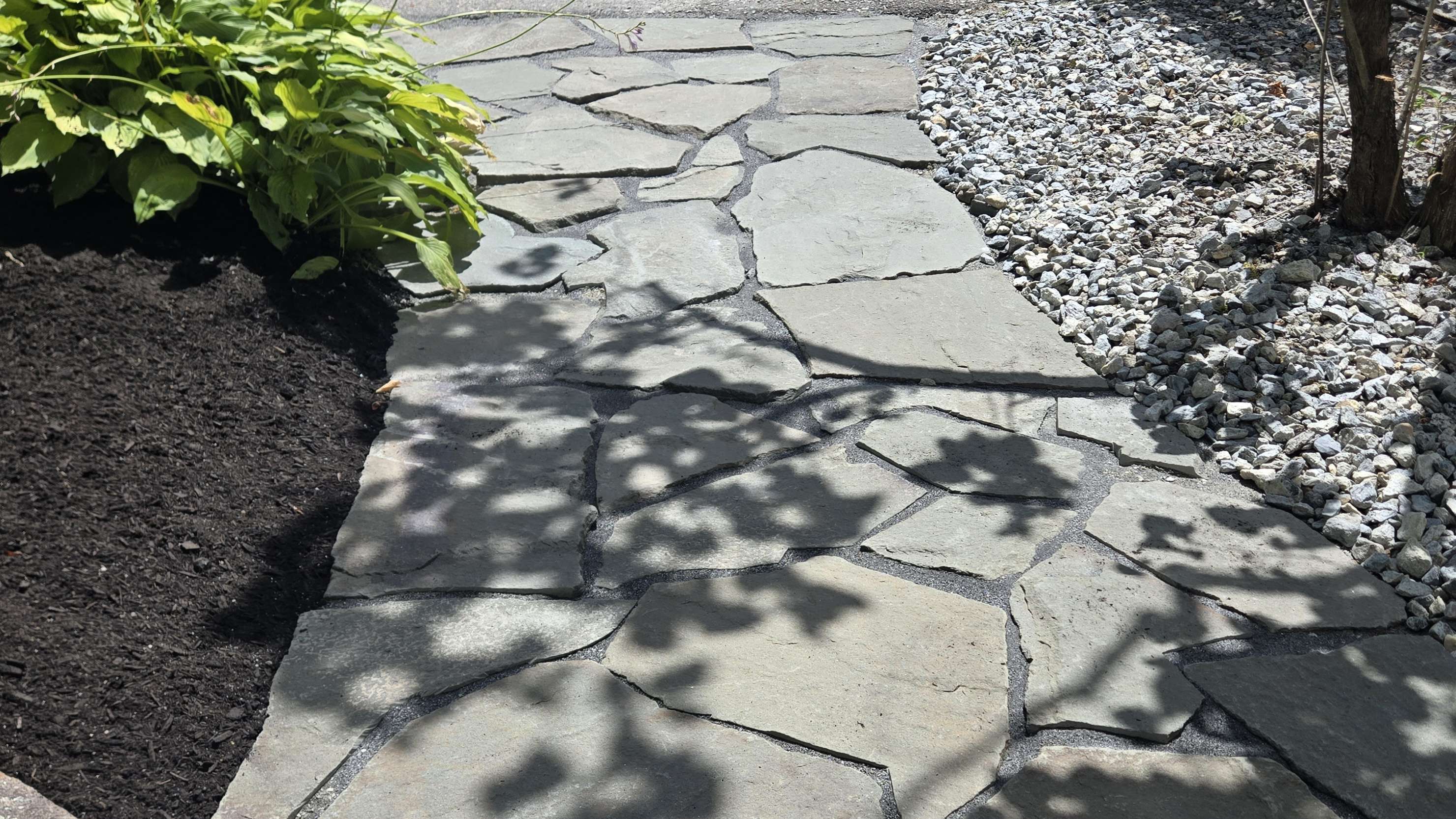 Professional flagstone walkway with mulched garden beds and stone borders