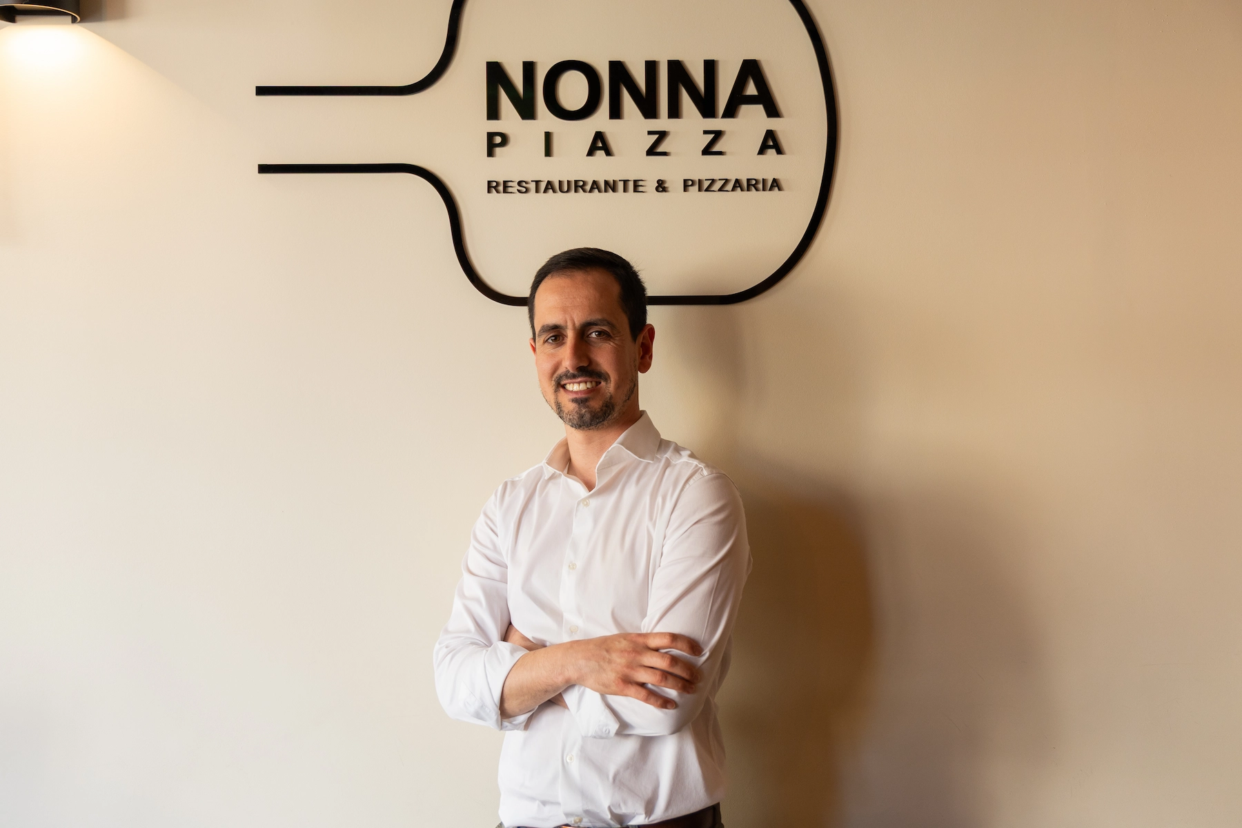 Responsável da Nonna Piazza em frente ao logótipo no Porto