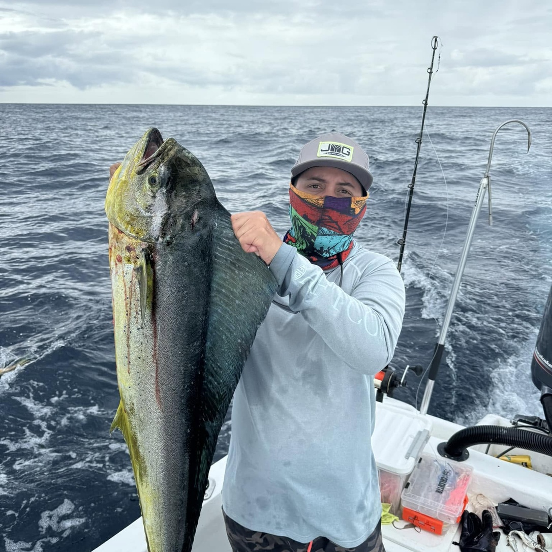 Francisco Chavarría, con el rostro cubierto, sostiene un pez grande a bordo de una embarcación en mar abierto.