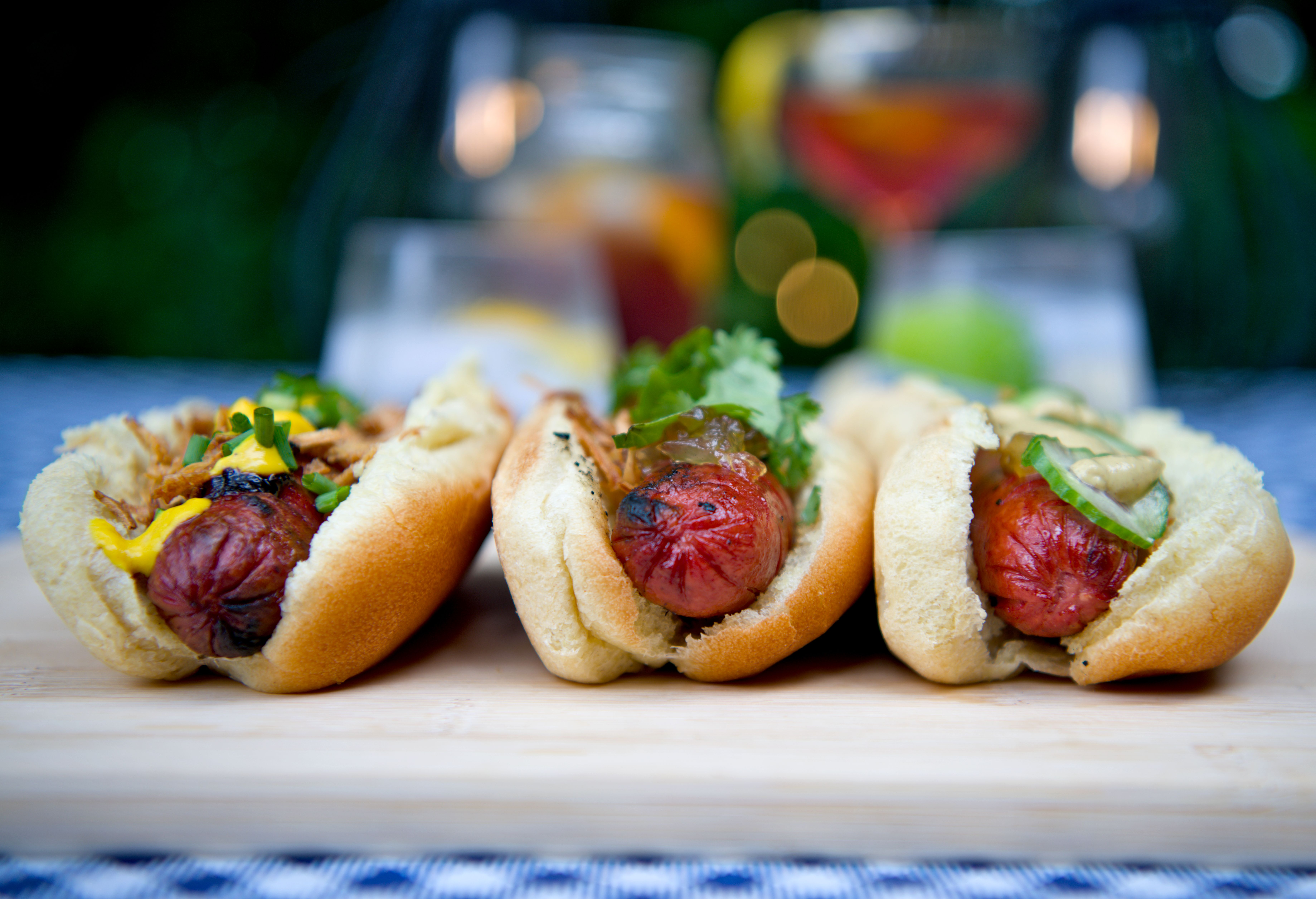 Gourmet hot dogs and craft cocktails arranged for a supper club table