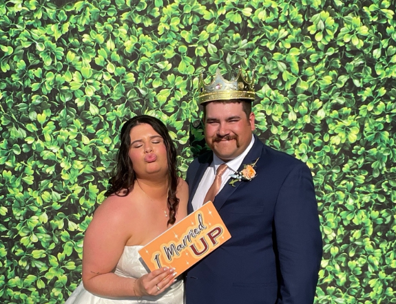 Bride and groom with props at Nashville wedding photobooth rental greenery backdrop