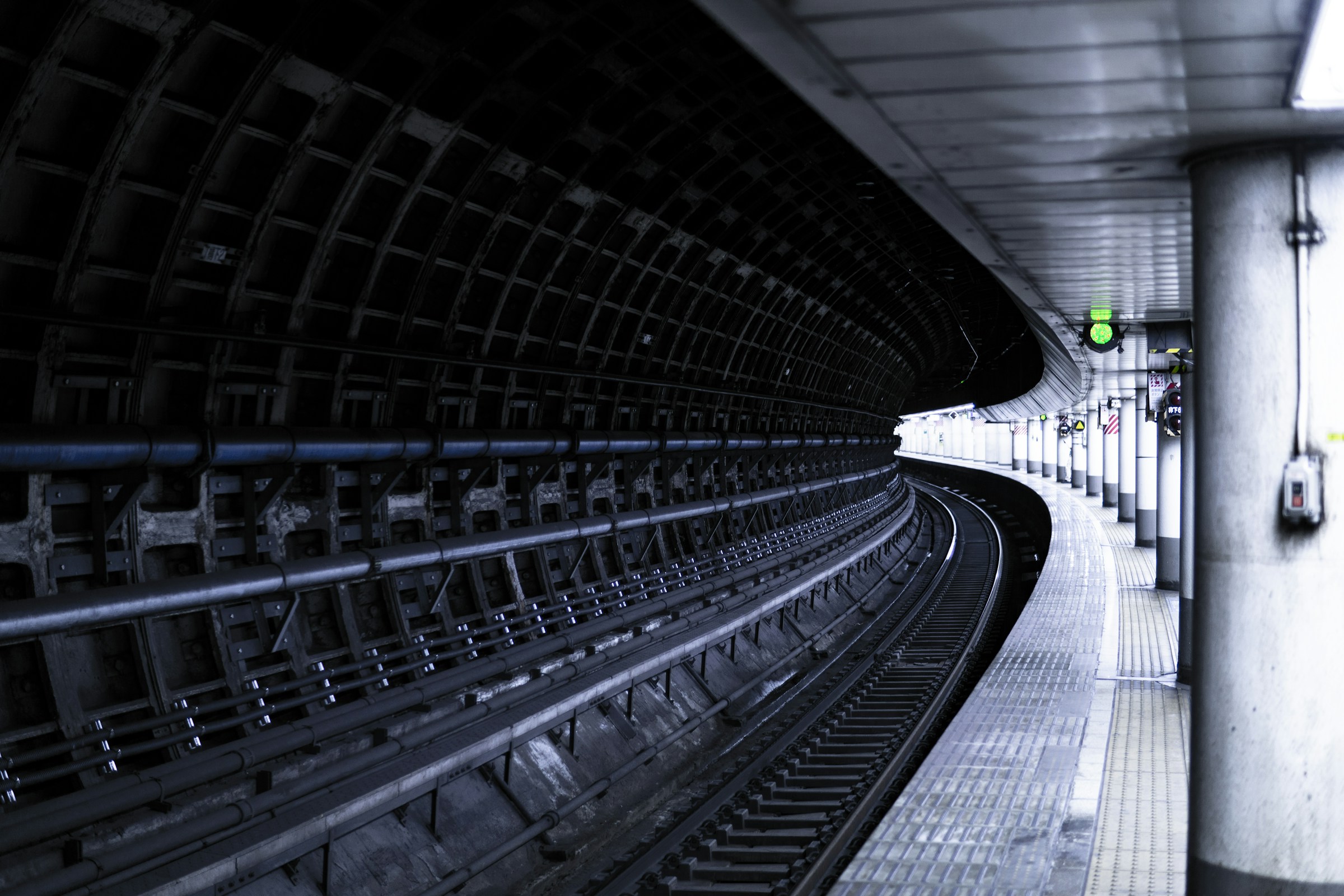 Dark subway station platform with curved tunnel and train tracks