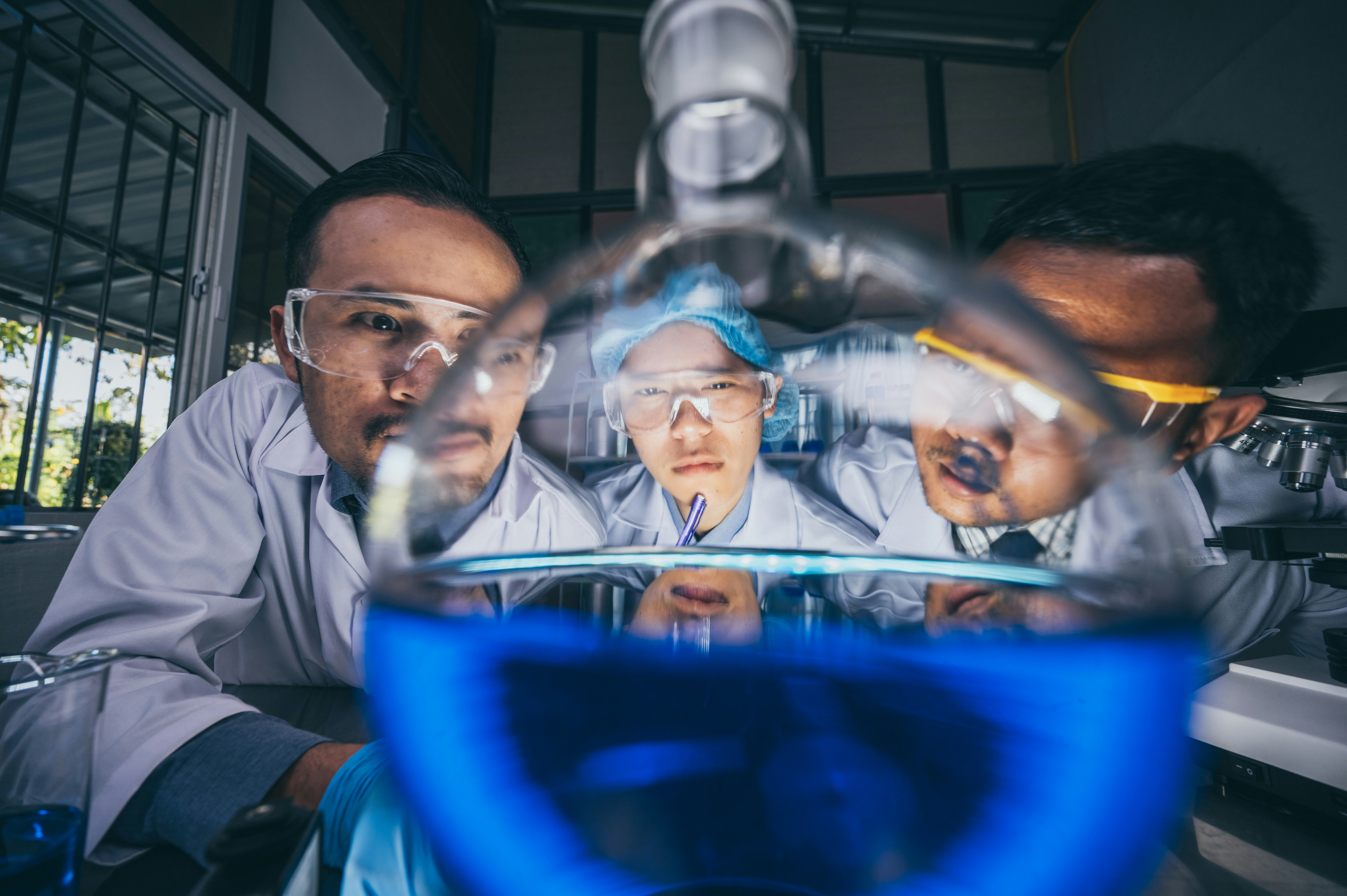 Scientists examining blue liquid in laboratory glassware