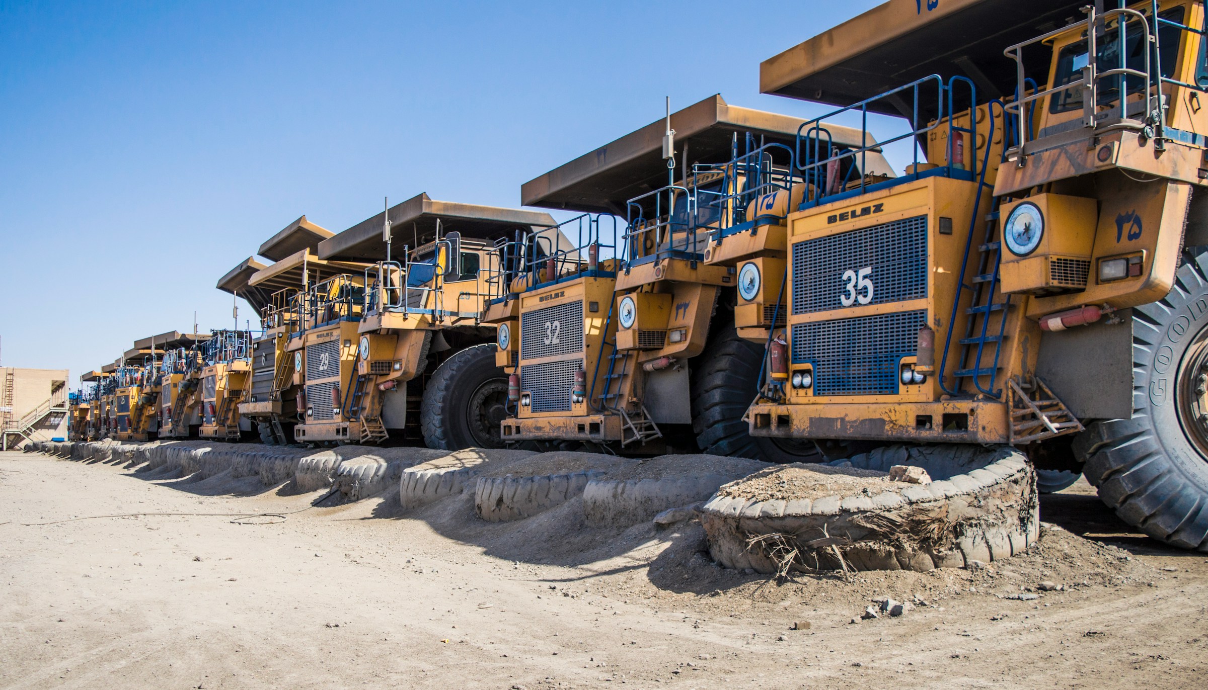 Row of large yellow mining dump trucks parked in a line