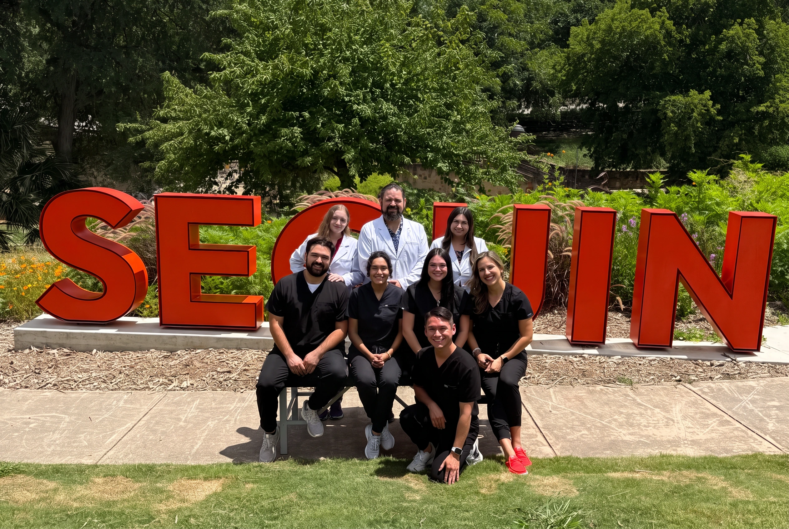 The full Pecan Country Chiropractic team in front of the Seguin sign