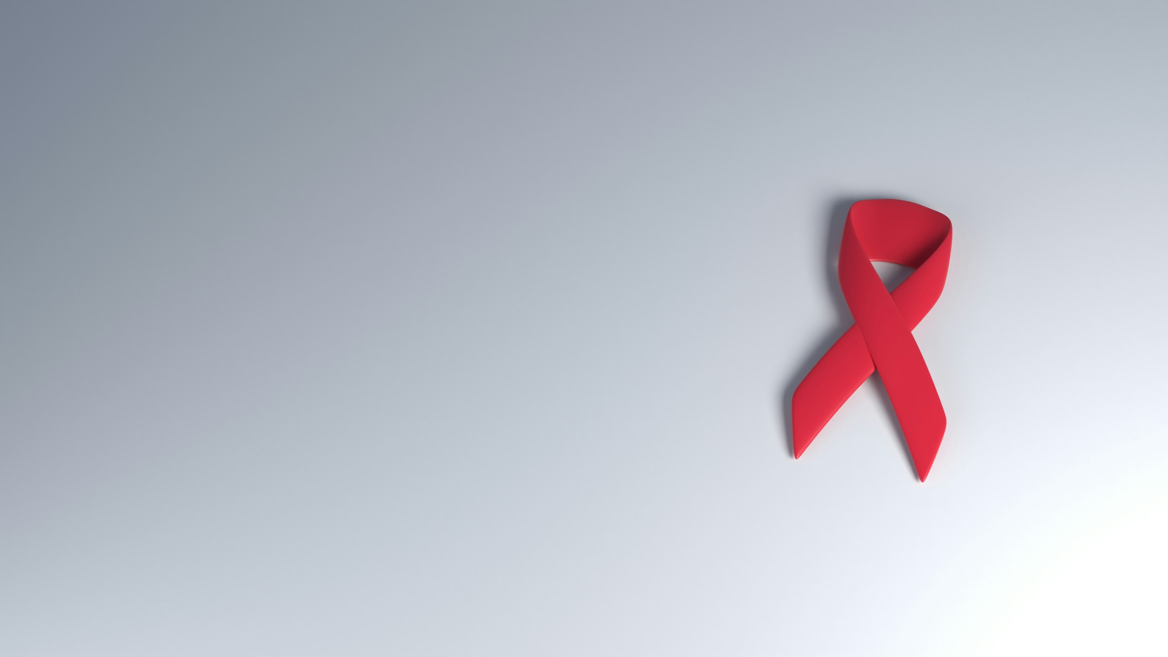 Red awareness ribbon symbolizing cancer awareness on gradient background