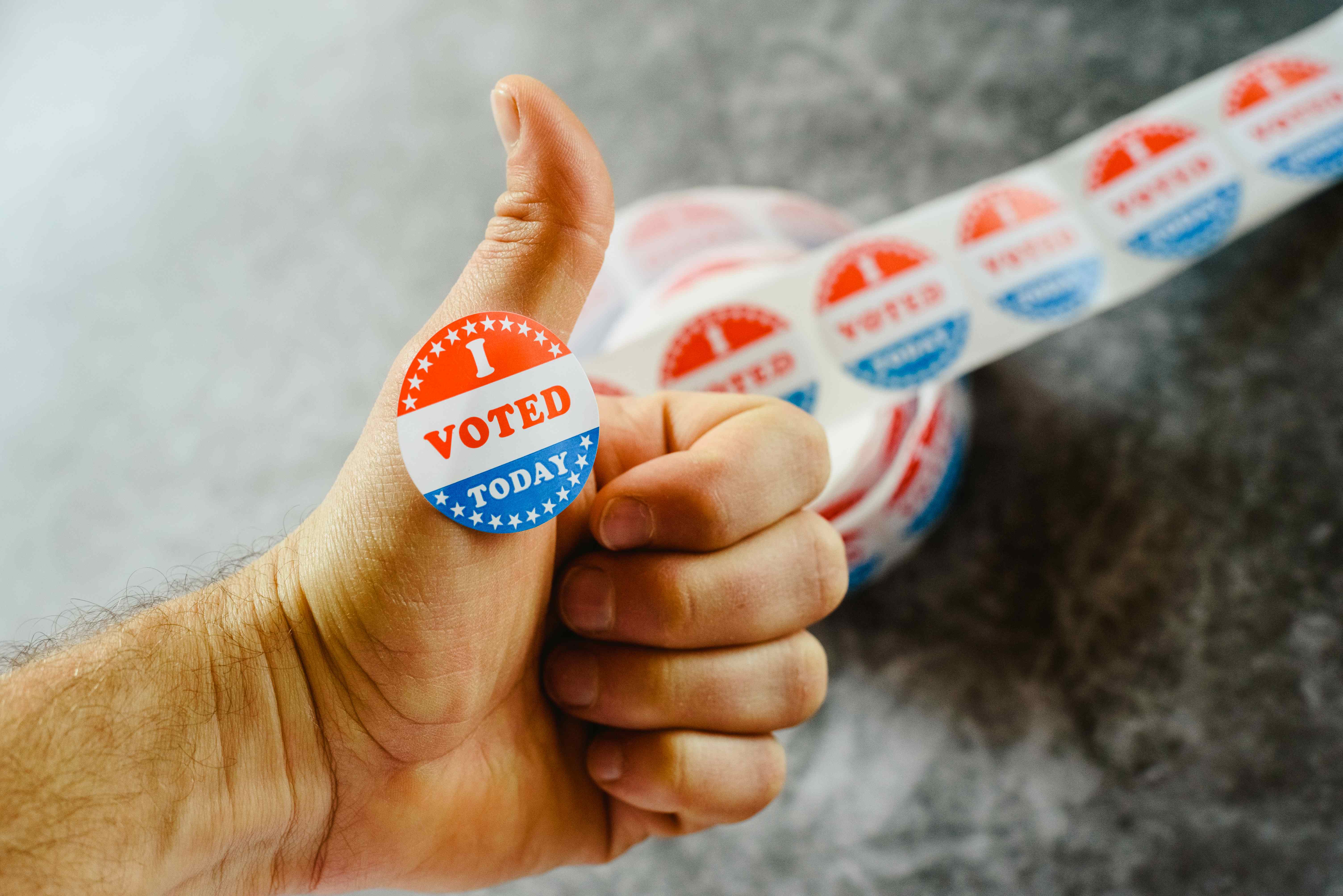 A hand with an I Voted Today sticker giving a thumbs up