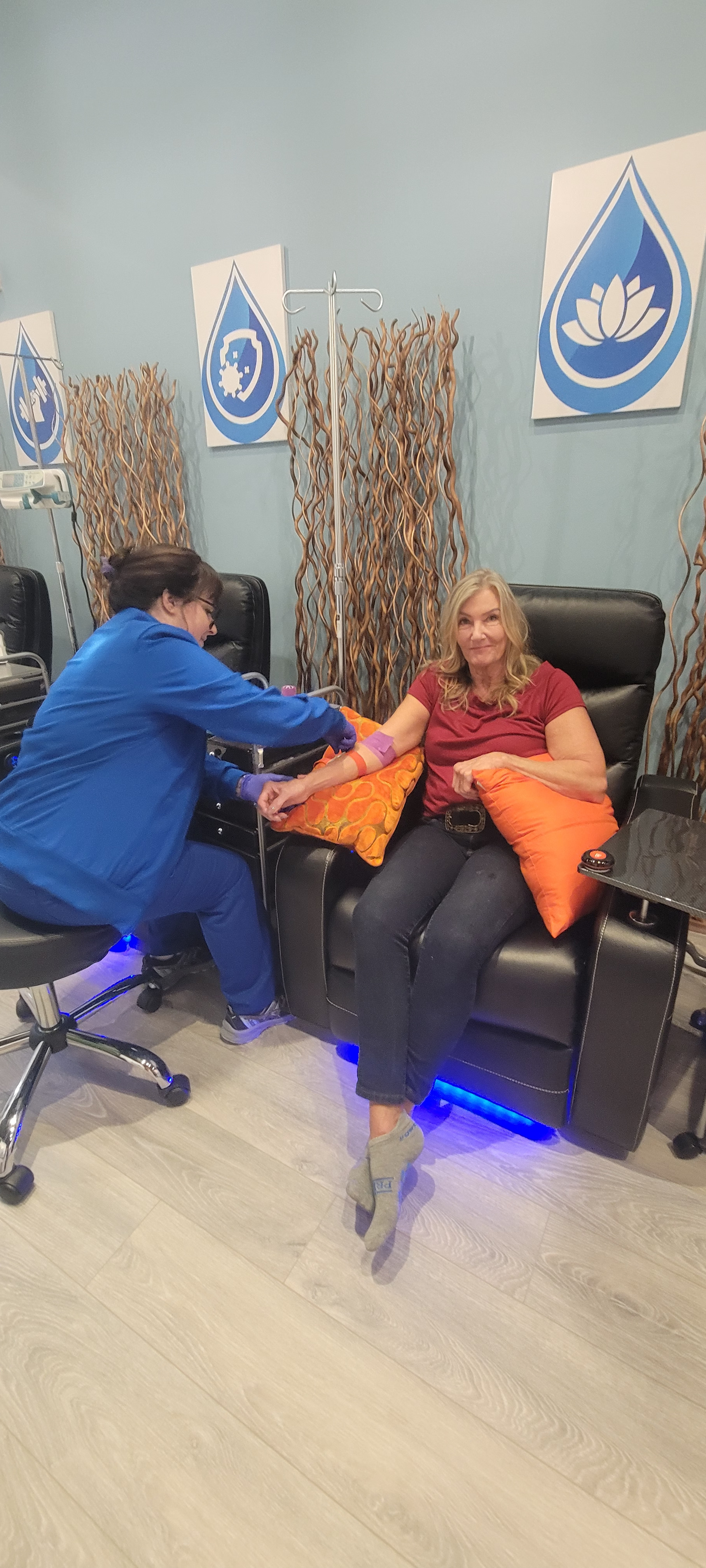 A Prime IV nurse administering an IV to a smiling, relaxed client in the Flemington lounge