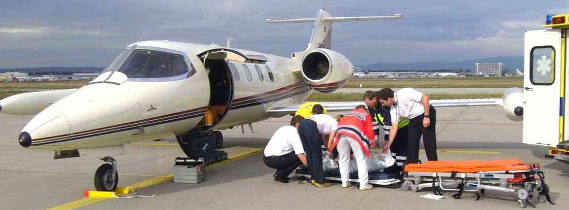 Equipo médico trasladando a un paciente en camilla hacia un jet sanitario en pista
